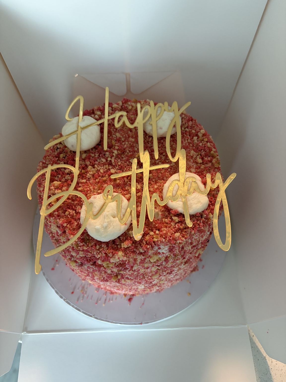 Strawberry crunch birthday cake with a gold Happy Birthday topper